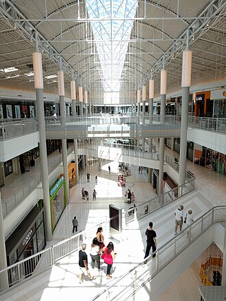 Corredor interno do shopping com três níveis de lojas